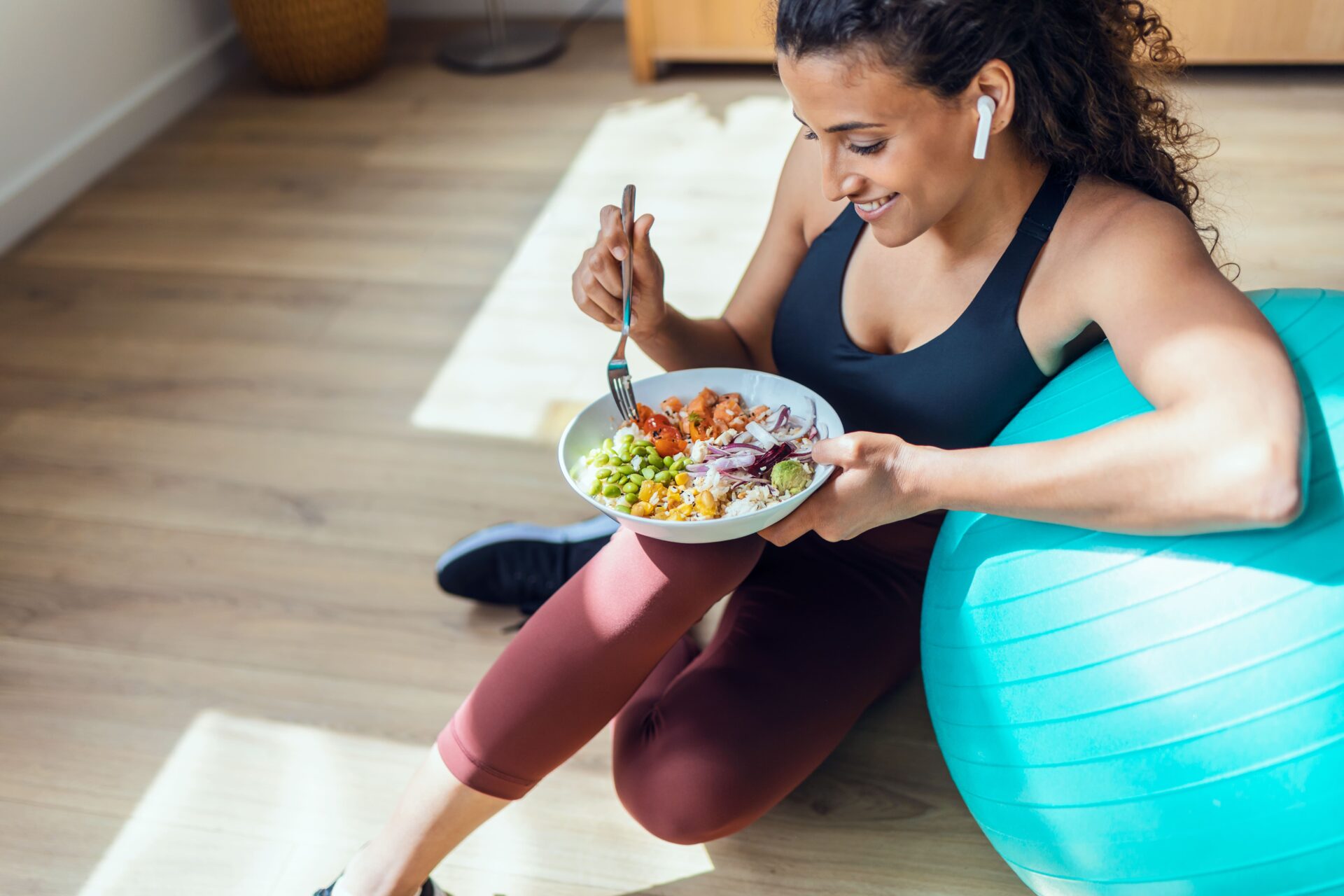 healthy-woman-sitting-down-to-eat-salad-after-exercising