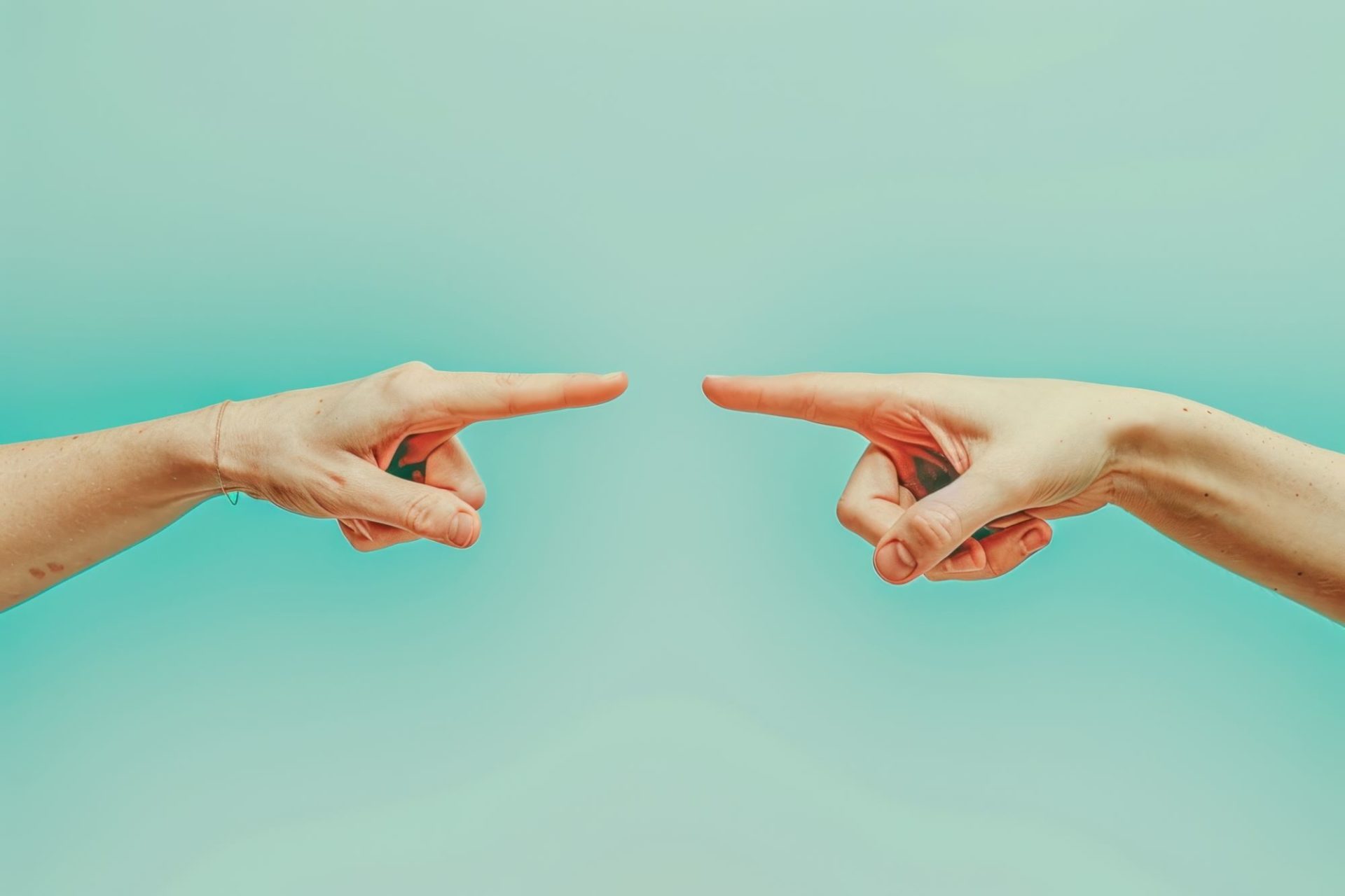 Hands pointing at each other in front of a blue background