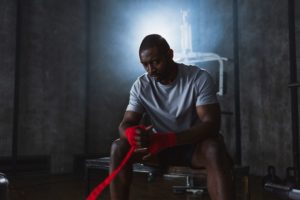 a man sat on a bench wrapping his hands for boxing.