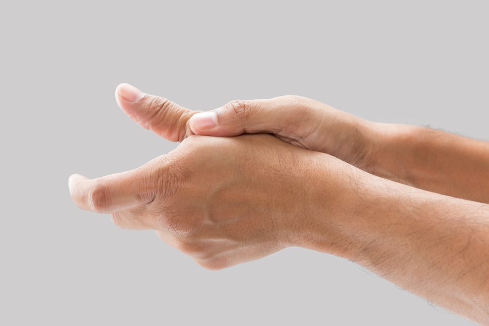 A man with thumb pain on a gray background.